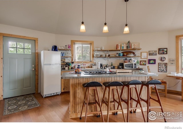 kitchen with white appliances, open shelves, a breakfast bar area, light wood-style flooring, and a center island