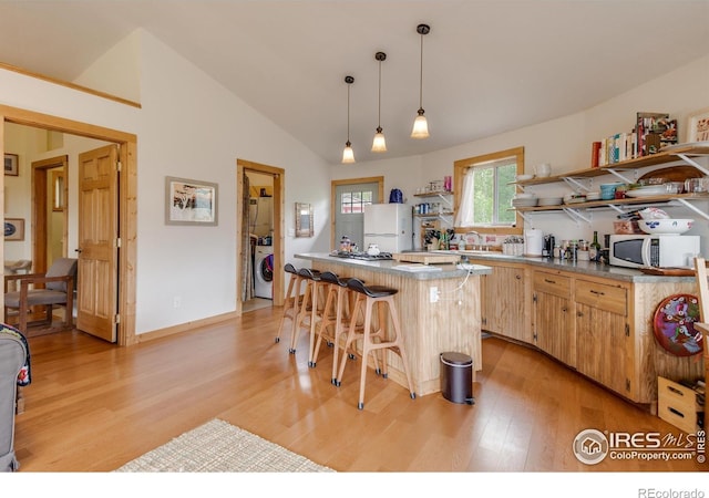kitchen with washer / clothes dryer, white appliances, open shelves, a breakfast bar area, and light wood finished floors