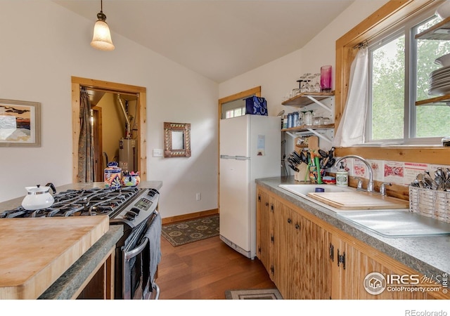kitchen with lofted ceiling, freestanding refrigerator, light wood finished floors, gas water heater, and stainless steel range with gas cooktop