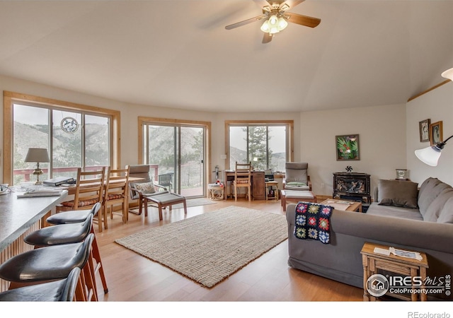 living room with vaulted ceiling, light wood finished floors, and a ceiling fan
