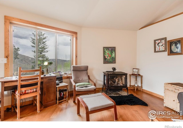 living area featuring a wood stove, lofted ceiling, a wealth of natural light, and light wood-style flooring