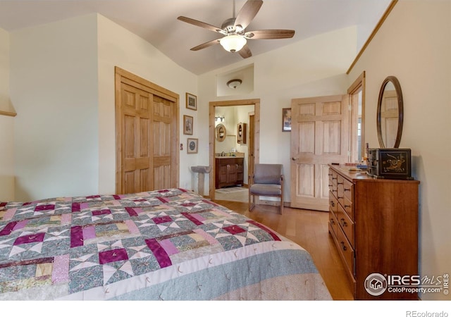 bedroom featuring a closet, ensuite bathroom, light wood finished floors, ceiling fan, and vaulted ceiling