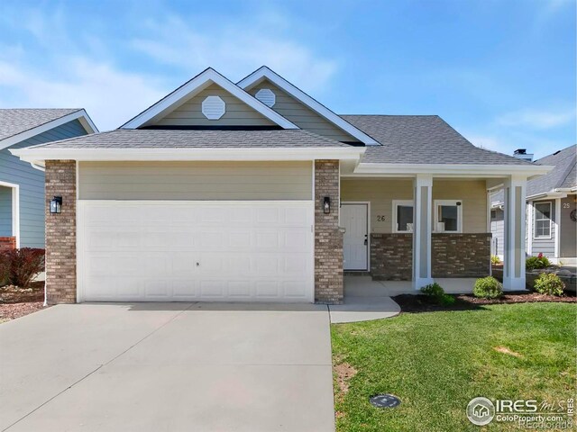 3822 W 11th St Unit 26, Greeley, CO 80634 - view of front of home featuring brick siding, driveway, a shingled roof, a front yard, and a garage