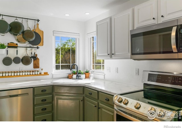 112 Cobble Dr, Windsor, CO 80550 - kitchen with white cabinetry, appliances with stainless steel finishes, green cabinets, and a sink