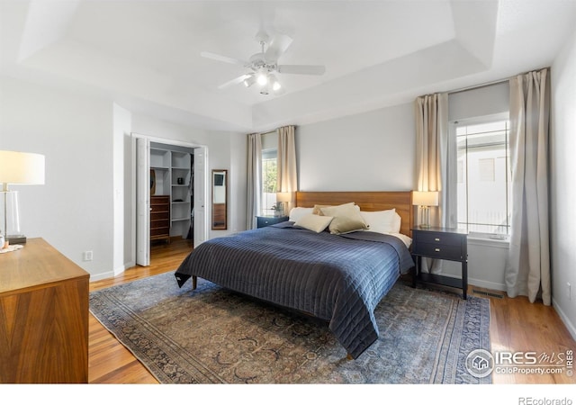 112 Cobble Dr, Windsor, CO 80550 - bedroom featuring wood finished floors, visible vents, a ceiling fan, a raised ceiling, and baseboards