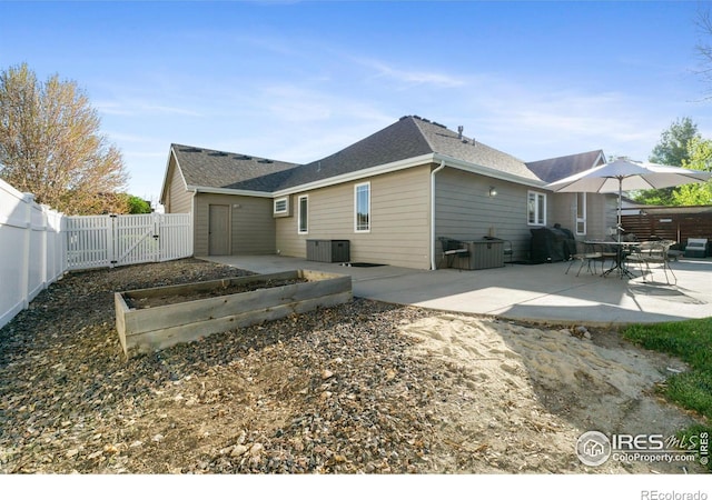 112 Cobble Dr, Windsor, CO 80550 - back of property with a vegetable garden, a patio area, central air condition unit, a fenced backyard, and a gate