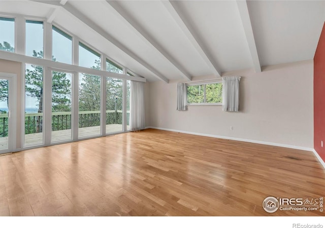 interior space with lofted ceiling with beams, baseboards, and light wood-style floors