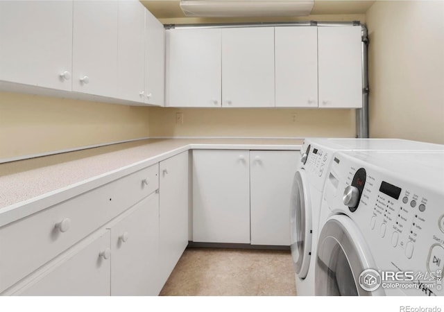 clothes washing area featuring washing machine and dryer and cabinet space