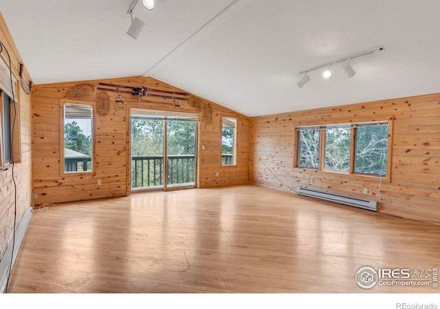 unfurnished room featuring wooden walls, baseboard heating, wood finished floors, and track lighting