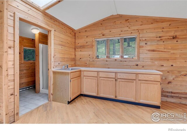 1629 Timber Ln, Boulder, CO 80304 - kitchen featuring light brown cabinetry, vaulted ceiling, wooden walls, a sink, and light wood-style flooring
