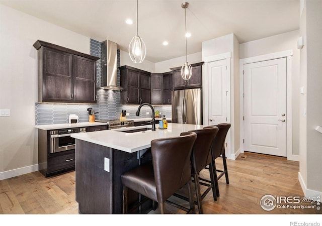 1481 Harebell St, Berthoud, CO 80513 - kitchen with dark brown cabinets, a kitchen breakfast bar, backsplash, wall chimney range hood, and appliances with stainless steel finishes