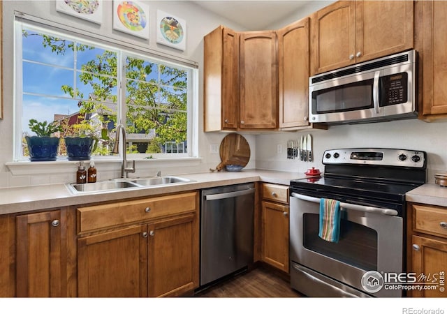 1278 Hummingbird Cir Unit D, Longmont, CO 80501 - kitchen featuring brown cabinets, a sink, stainless steel appliances, dark wood-type flooring, and light countertops