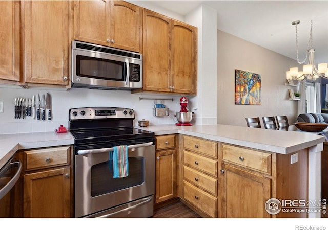 1278 Hummingbird Cir Unit D, Longmont, CO 80501 - kitchen with a peninsula, light countertops, a chandelier, and appliances with stainless steel finishes