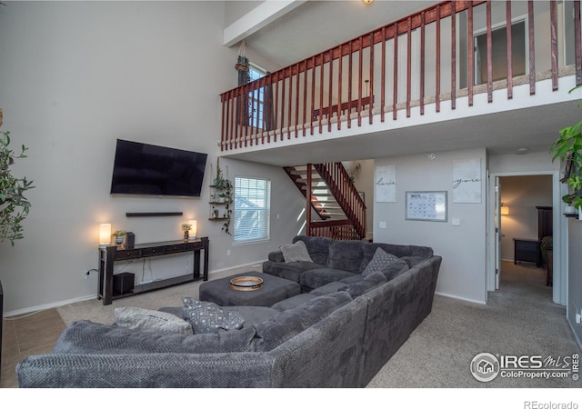 carpeted living area featuring a towering ceiling, stairs, and baseboards