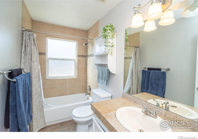 bathroom with an inviting chandelier, toilet, shower / bath combo with shower curtain, tile patterned flooring, and vanity