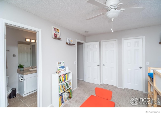 recreation room with a textured ceiling, a ceiling fan, and a sink