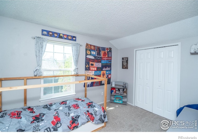 bedroom with vaulted ceiling, a textured ceiling, carpet, and a closet