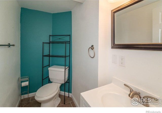 half bathroom featuring tile patterned floors, toilet, baseboards, and vanity
