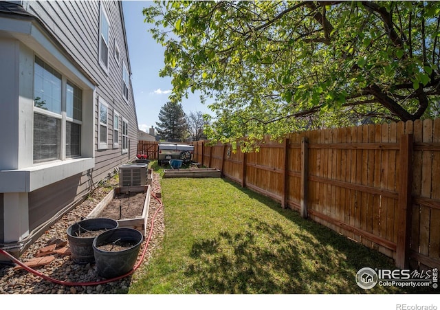 view of yard featuring a fenced backyard, a garden, and central AC