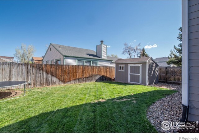 view of yard featuring a storage shed, a trampoline, an outbuilding, and a fenced backyard