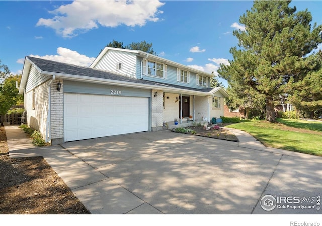 traditional home with driveway, brick siding, covered porch, an attached garage, and a front lawn