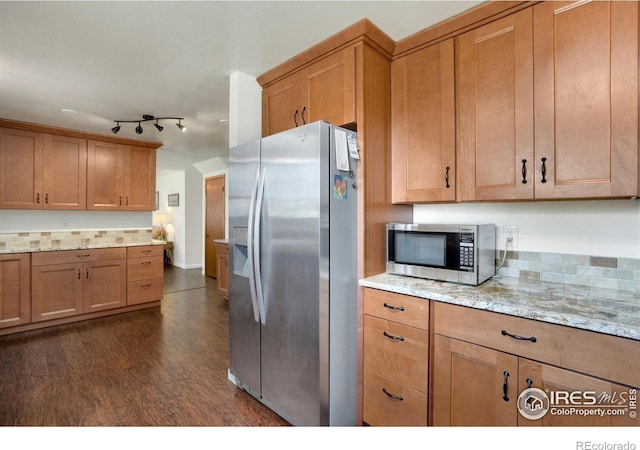 kitchen featuring dark wood finished floors, appliances with stainless steel finishes, light stone counters, and brown cabinets