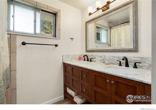 bathroom featuring backsplash, double vanity, baseboards, and a sink