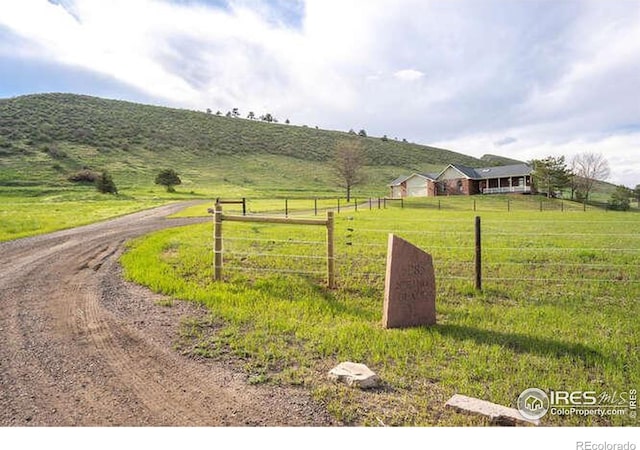 exterior space featuring fence, a rural view, and driveway