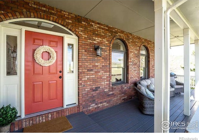doorway to property with a porch and brick siding