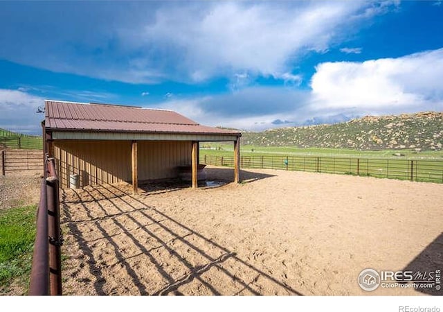 exterior space featuring an exterior structure, a carport, an enclosed riding area, an outbuilding, and a view of rural / pastoral area