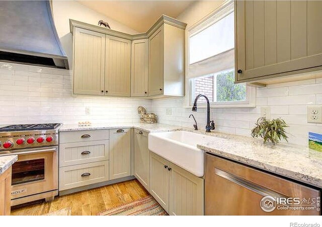 kitchen featuring custom range hood, luxury range, a sink, and backsplash