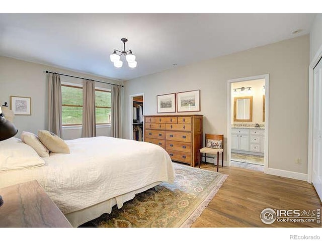 bedroom featuring a chandelier, a closet, wood finished floors, a spacious closet, and baseboards