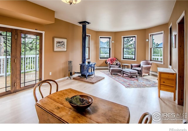 dining room with a wood stove, light wood finished floors, and healthy amount of natural light