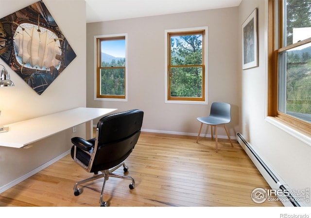 office area with wood finished floors, plenty of natural light, baseboards, and baseboard heating