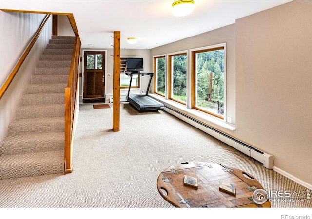 exercise area featuring carpet floors, a baseboard heating unit, and baseboards