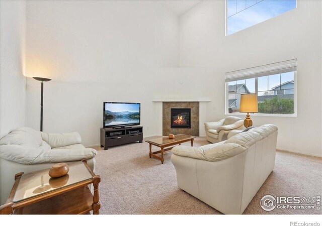 living area with light carpet, a high ceiling, plenty of natural light, and a tile fireplace