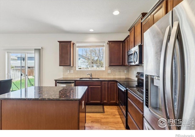 kitchen featuring stainless steel appliances, a sink, light wood finished floors, plenty of natural light, and recessed lighting