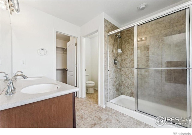 bathroom with toilet, tile patterned flooring, a shower stall, and a sink