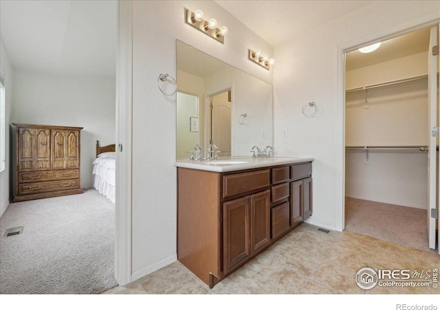 ensuite bathroom featuring double vanity and a walk in closet