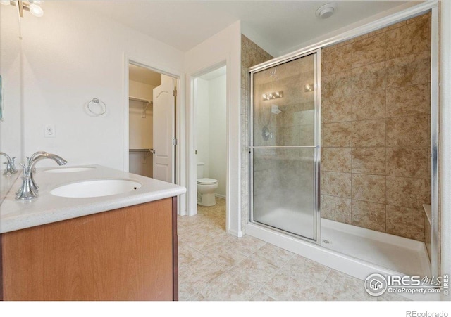bathroom with a shower stall, tile patterned floors, a sink, toilet, and a spacious closet