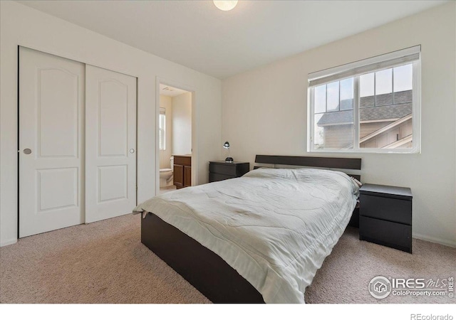 bedroom with carpet flooring, ensuite bathroom, a closet, and baseboards