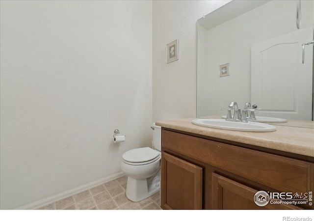 bathroom featuring vanity, toilet, and baseboards