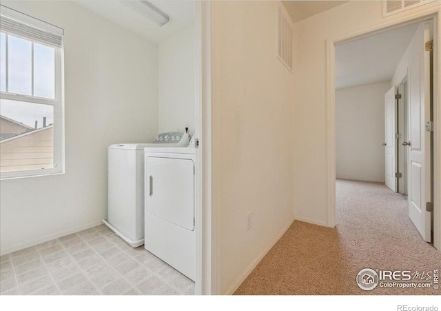 laundry area with washer and dryer and light colored carpet
