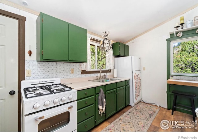 kitchen with lofted ceiling, green cabinets, white appliances, a healthy amount of sunlight, and a sink
