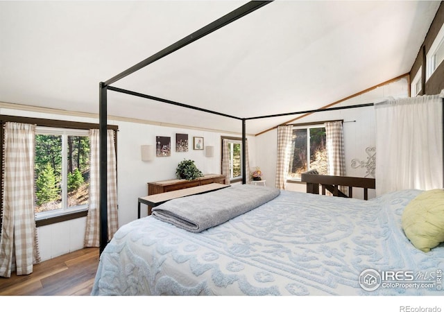 bedroom featuring multiple windows, wood finished floors, and lofted ceiling