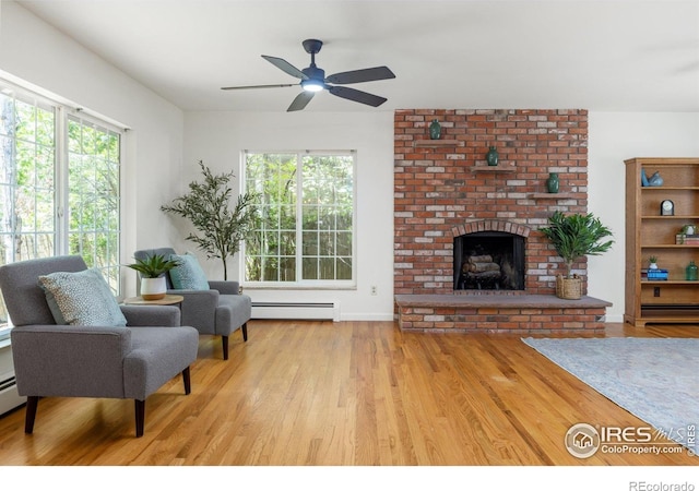 living area with a fireplace, ceiling fan, plenty of natural light, and wood finished floors