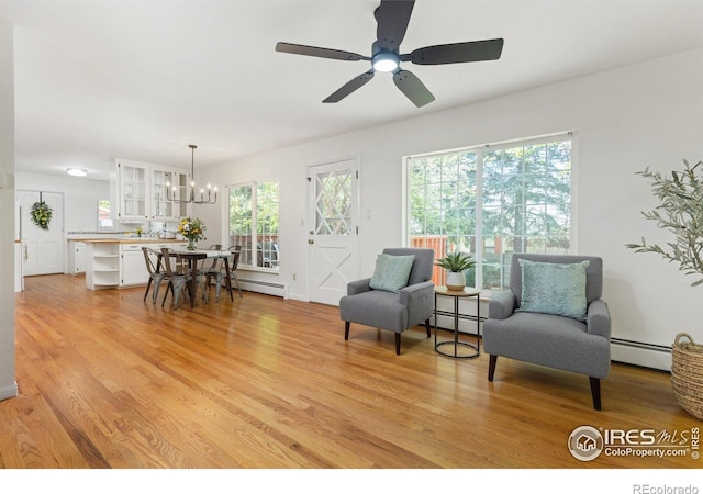 sitting room featuring a healthy amount of sunlight, baseboard heating, and light wood-style flooring