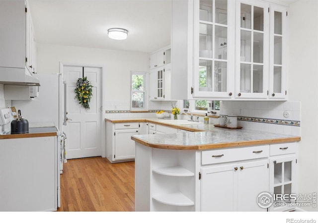 kitchen with a peninsula, tasteful backsplash, light wood-type flooring, white cabinetry, and light countertops
