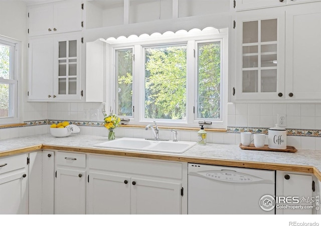 kitchen with white cabinetry, white dishwasher, and a sink