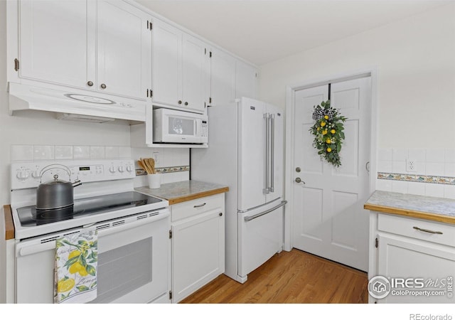 kitchen featuring white appliances, under cabinet range hood, light wood finished floors, white cabinetry, and backsplash